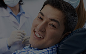 Smiling man wearing blue plaid shirt in dental chair