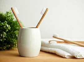 Two toothbrushes in cup next to towel and other toothbrushes
